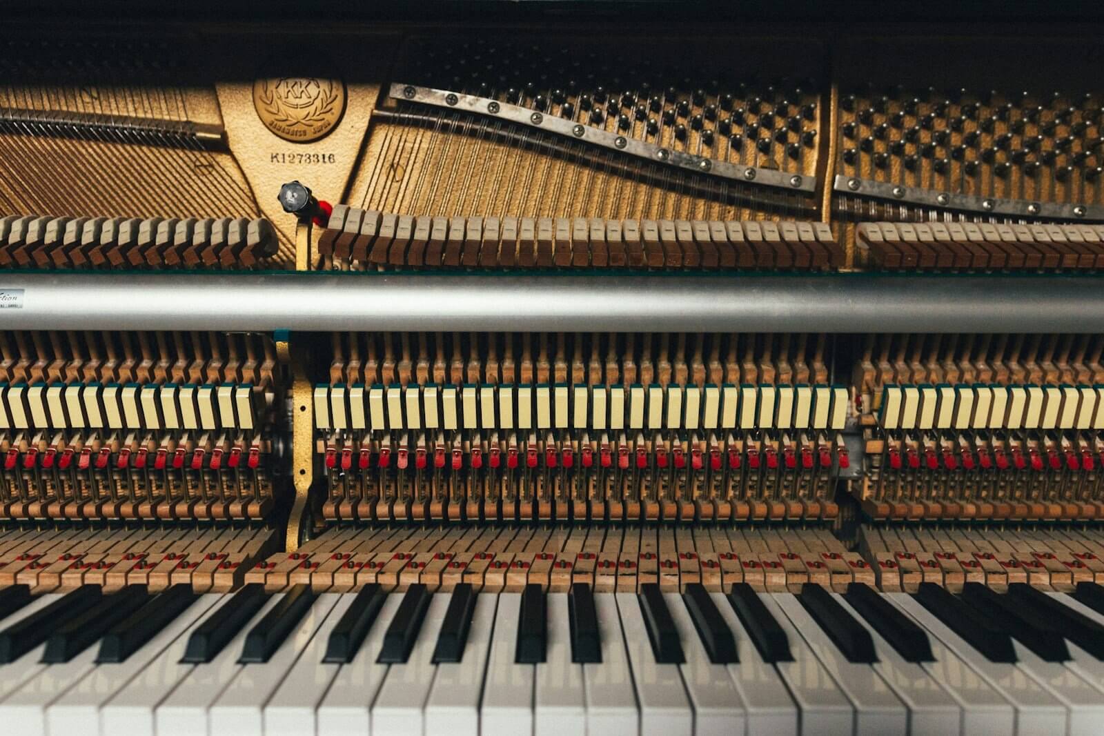 Inside an upright piano, showing the hammers, strings and keys